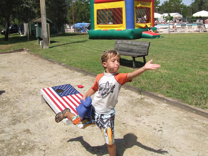 Child playing on the park with an American cornhole in the background 